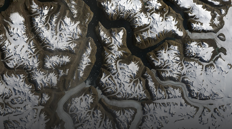 Aerial imagery showing rugged snow-covered mountain terrain with deep valleys and dark waterways