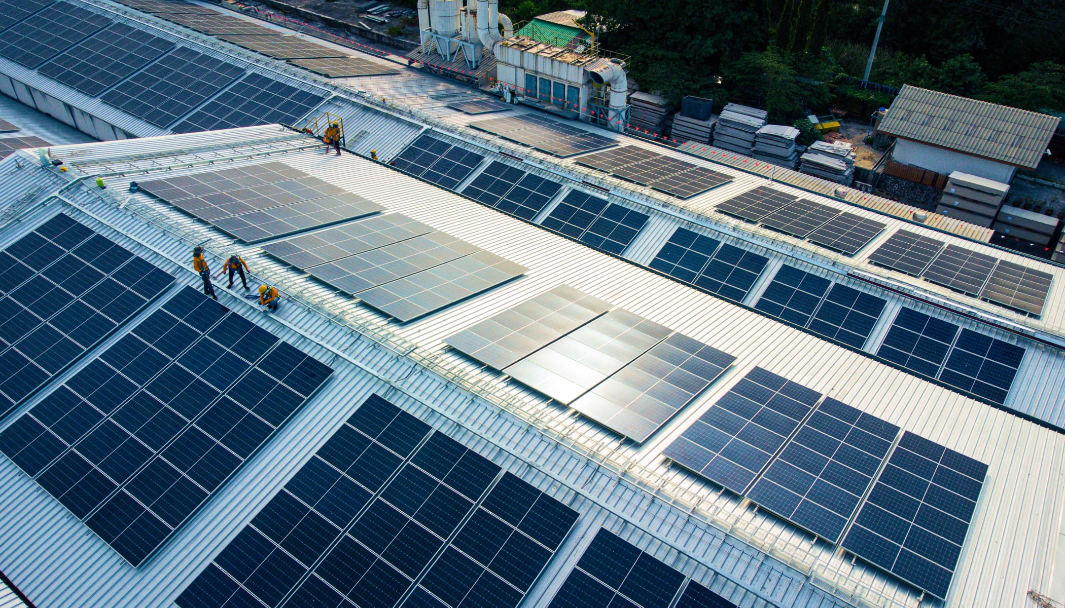 Rows of solar panels on a commercial roof being inspected by maintenance crews